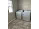 Bright laundry room features a new washer, dryer, tile floors, and shelving at 1077 Kafka Dr, Fuquay Varina, NC 27526