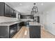 New kitchen features dark cabinets, stainless appliances, an island, and stylish hanging light fixtures at 1122 Briar Rose Ln, Durham, NC 27704
