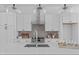 Bright kitchen with white cabinetry, quartz countertops, and a central island with a prep sink at 2002 Moody Ln, Durham, NC 27701