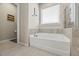 Bathroom featuring a soaking tub with tile surround and a window at 2233 Kanata Mills Rd, Wake Forest, NC 27587