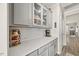 Butler's pantry featuring white quartz counters, grey cabinets with glass fronts, and subway tile back splash at 2233 Kanata Mills Rd, Wake Forest, NC 27587