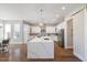 Open-concept kitchen featuring white cabinets, a large island with marble countertop and seating, and stainless steel appliances at 2632 Jordan Pointe Blvd, New Hill, NC 27562