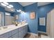 Bathroom with double sink vanity, large mirror, and blue walls and cabinets at 310 Chub Lake St, Roxboro, NC 27573