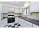 Cozy kitchen featuring white cabinets, black countertops, and checkered flooring at 3775 Guess Rd # 36, Durham, NC 27705