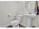 Cozy half bath featuring modern fixtures, a pedestal sink, and decorative round mirror at 380 Grameta Ln, Lillington, NC 27546