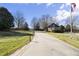 Long driveway leading to a private community gate, stone guardhouse, and mature trees at 40 Park Meadow Ln, Youngsville, NC 27596