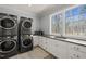 Well-lit laundry room with stackable washer/dryer, white cabinets, and a scenic window view at 40 Park Meadow Ln, Youngsville, NC 27596