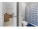 Bathroom with patterned shower curtain seen from doorway, featuring a toilet with blue rug and beige walls at 400 Oxford Park Blvd, Oxford, NC 27565
