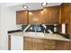 Kitchen sink with wood cabinetry, granite countertop, black and white tile backsplash, and stainless steel faucet at 4905 Will-O-Dean Rd, Raleigh, NC 27616