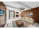 Bright living room featuring a white brick fireplace, wood paneling, furniture and a ceiling fan at 4905 Will-O-Dean Rd, Raleigh, NC 27616