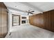 Bright living room featuring a white brick fireplace, wood paneling, a ceiling fan and outdoor access at 4905 Will-O-Dean Rd, Raleigh, NC 27616