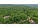 An aerial view reveals the roofs of houses nestled among a forest of lush green trees at 5507 Eagles Nest Trl, Snow Camp, NC 27349