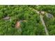 Aerial shot of a gray house among the lush green trees with a winding road nearby at 5507 Eagles Nest Trl, Snow Camp, NC 27349
