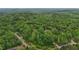 An aerial view shows a winding road leading to houses hidden among the lush green trees at 5507 Eagles Nest Trl, Snow Camp, NC 27349