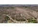 Aerial view shows neighborhood homes nestled amongst barren trees under a partially cloudy sky at 5507 Eagles Nest Trl, Snow Camp, NC 27349