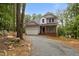 Charming two-story home featuring a gravel driveway, attached garage, and welcoming front porch nestled among mature trees at 5507 Eagles Nest Trl, Snow Camp, NC 27349