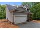 Side view of a two-story home with two car garage and covered front porch under a gray roof at 5507 Eagles Nest Trl, Snow Camp, NC 27349