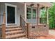 Close up view of the welcoming front porch that features hanging flower baskets and brick base and wooden stairs at 5507 Eagles Nest Trl, Snow Camp, NC 27349
