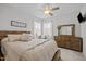A bright bedroom with a wood framed bed, ceiling fan, natural light and a wooden dresser at 63 Capewood Ct, Garner, NC 27529