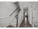 Hallway with carpeted stairs and wood floors leading into a room with a hallway with white wainscoting at 63 Capewood Ct, Garner, NC 27529