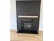 Modern fireplace with black herringbone patterned wall and light wood mantel at 82 Cool Creek Dr, Willow Springs, NC 27592