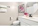 Clean half bathroom with white vanity, oval mirror, and decorative artwork at 8412 Pierce Olive Rd, Apex, NC 27539