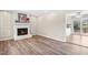 Cozy living room featuring a white fireplace, wood flooring, and an open doorway to the kitchen at 8412 Pierce Olive Rd, Apex, NC 27539