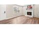 Bright living room with a white brick fireplace, wood floors, and natural light from a large window at 8412 Pierce Olive Rd, Apex, NC 27539