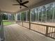 Covered wooden porch with black railings, ceiling fan and a tranquil wooded view at 9231 Bear Run Ln, Middlesex, NC 27557