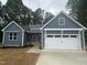 Charming blue single-story home featuring a two-car garage and a well-manicured front yard surrounded by tall trees at 9231 Bear Run Ln, Middlesex, NC 27557