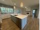 Kitchen island with a view of an open concept living room with a fireplace and windows, plus wood floors at 9231 Bear Run Ln, Middlesex, NC 27557