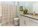 Well-lit bathroom featuring a sink vanity, toilet, and shower with palm tree patterned curtain at 1 Parker Pond Ct, Durham, NC 27703