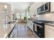 Bright kitchen featuring stainless steel appliances, white cabinets, and a view to sunroom through sliding glass doors at 1 Parker Pond Ct, Durham, NC 27703