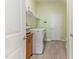 Laundry room with washer, dryer, and storage cabinet with tiled floor and light green walls at 1 Parker Pond Ct, Durham, NC 27703