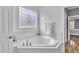 Bathroom showcasing a corner soaking tub with tile surround, brushed nickel fixtures, and natural light at 10 Holden Ct, Youngsville, NC 27596