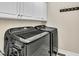 Modern laundry room featuring a front load washer and dryer with storage cabinets above at 10 Holden Ct, Youngsville, NC 27596