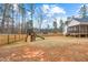 Large fenced backyard with a playset, mature trees, and a covered porch at 105 Shawnee Drive, Louisburg, NC 27549