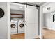 Bright laundry room featuring a sliding barn door and modern washer and dryer units at 112 Hartland Ct, Raleigh, NC 27614