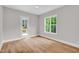A bright, empty bedroom featuring hardwood floors, natural light, and a door leading to a balcony at 12912 Grey Willow Dr, Raleigh, NC 27613