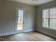 Bright bedroom with large window and door to deck, showcasing natural light and hardwood floors at 12912 Grey Willow Dr, Raleigh, NC 27613
