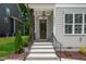 Inviting entryway with a glass paneled wooden door, black railings, and concrete steps at 12912 Grey Willow Dr, Raleigh, NC 27613