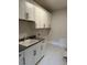 Well-organized laundry room with ample white cabinetry, gray countertop, and tiled floor at 12912 Grey Willow Dr, Raleigh, NC 27613