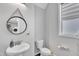 Bathroom featuring modern fixtures, including a round mirror, a pedestal sink, and a toilet at 173 E Wilson St, Clayton, NC 27520