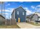 View of a blue house with a yellow door, set beside a wooden fence and green surroundings at 173 E Wilson St, Clayton, NC 27520