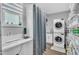 Well-lit laundry room featuring a sink, shelving, and a modern, stacked washer and dryer set at 173 E Wilson St, Clayton, NC 27520