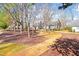 Backyard featuring a curved brick walkway and mature trees, creating a serene outdoor setting at 2 Poplar Ave, Elon, NC 27244