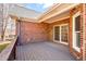 Back deck of a brick home with a wooden railing, patio door, and privacy wall at 2 Poplar Ave, Elon, NC 27244