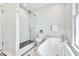 Well-lit bathroom with glass-enclosed shower, tub, and hexagon tile flooring at 301 Hillsborough St, Chapel Hill, NC 27514