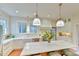 A bright kitchen boasts a large island with seating, stainless steel appliances, and pendant lighting at 301 Hillsborough St, Chapel Hill, NC 27514