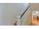 View of a bright staircase, with white railing and hardwood steps and an open door to the kitchen at 301 Hillsborough St, Chapel Hill, NC 27514